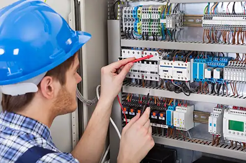 Technician inspecting MS/TP network wiring in an electrical panel.