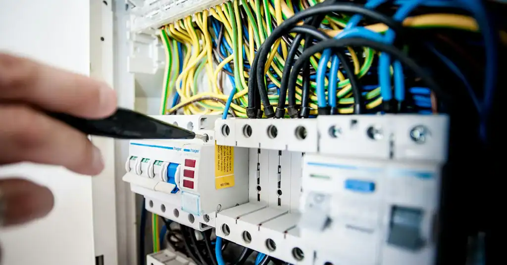 Technician working on network wiring in an electrical panel.