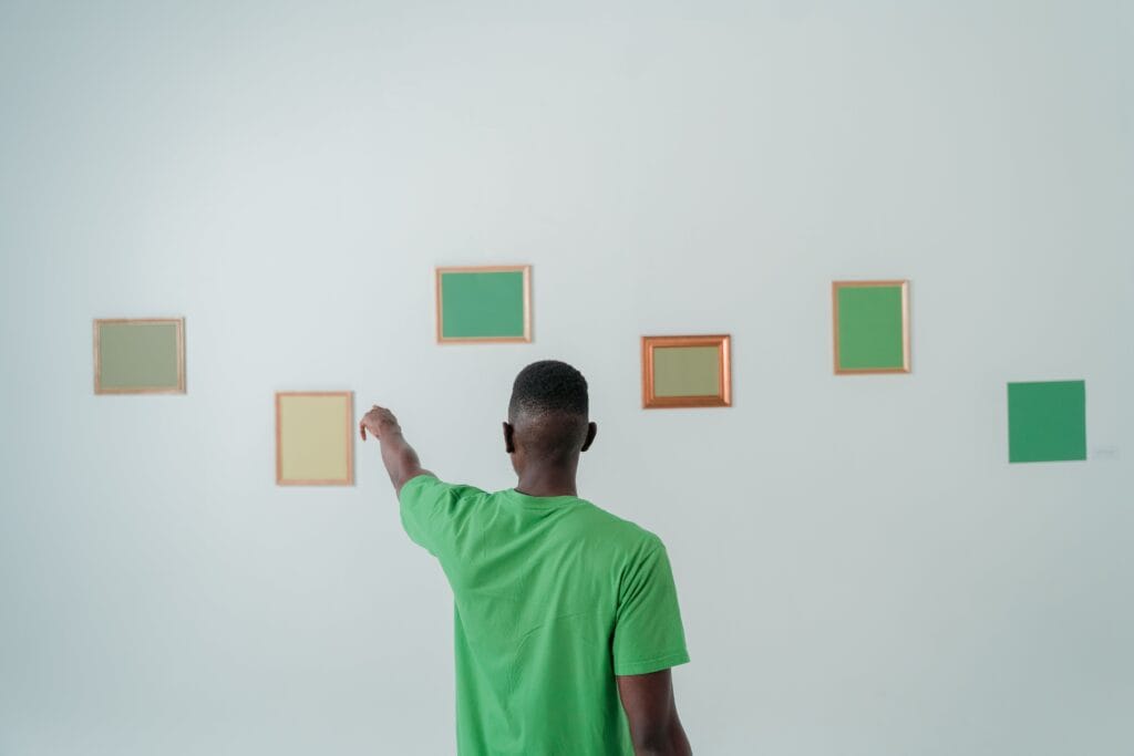 Man pointing at framed green artwork on wall
