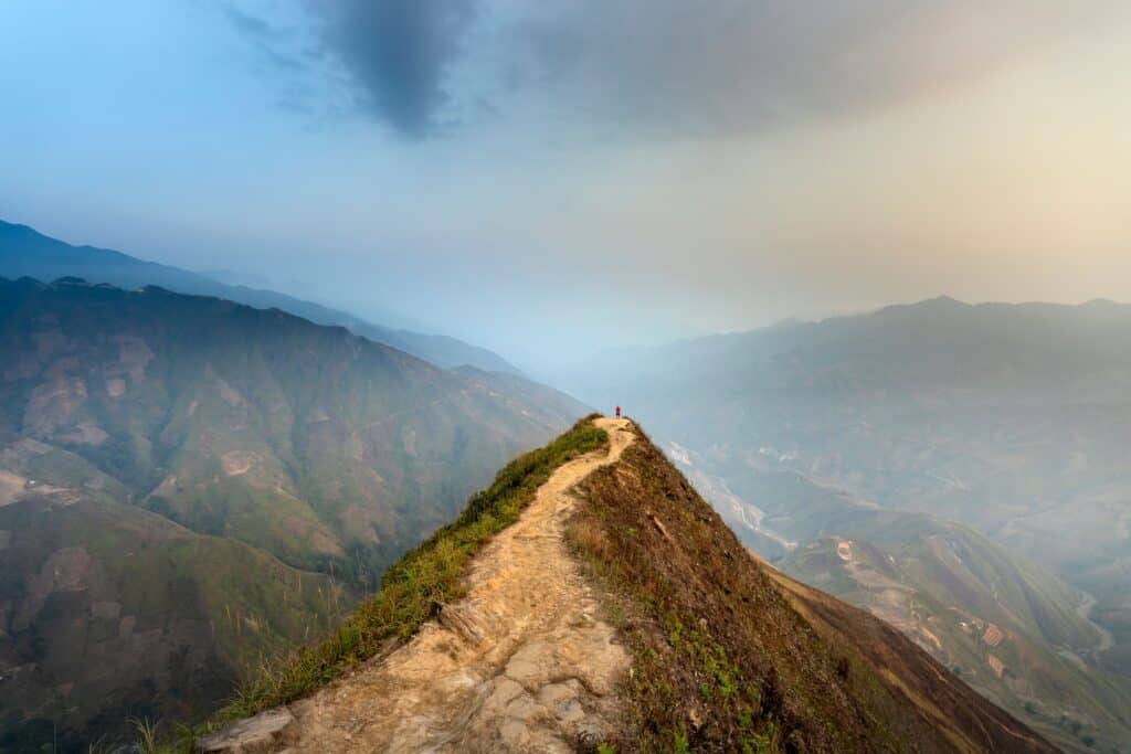 Hiker standing on narrow mountain ridge trail